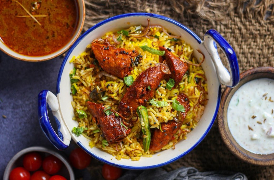 Chicken biryani with raita and curry, ready for a table