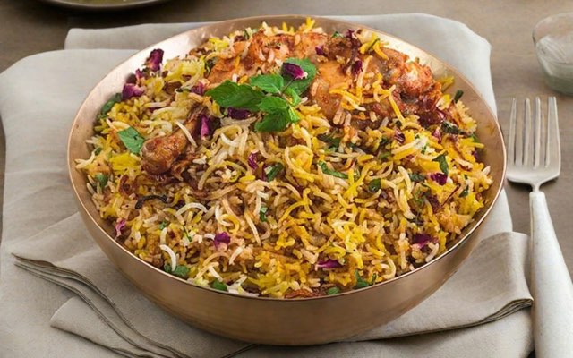Dum biryani in a copper handi, garnished with fried onions and mint